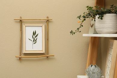 Photo of Green plant on shelving unit near beige wall with bamboo frame