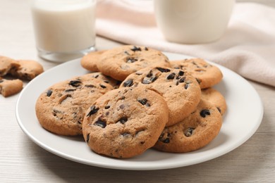Photo of Plate with delicious chocolate chip cookies on white wooden table, closeup