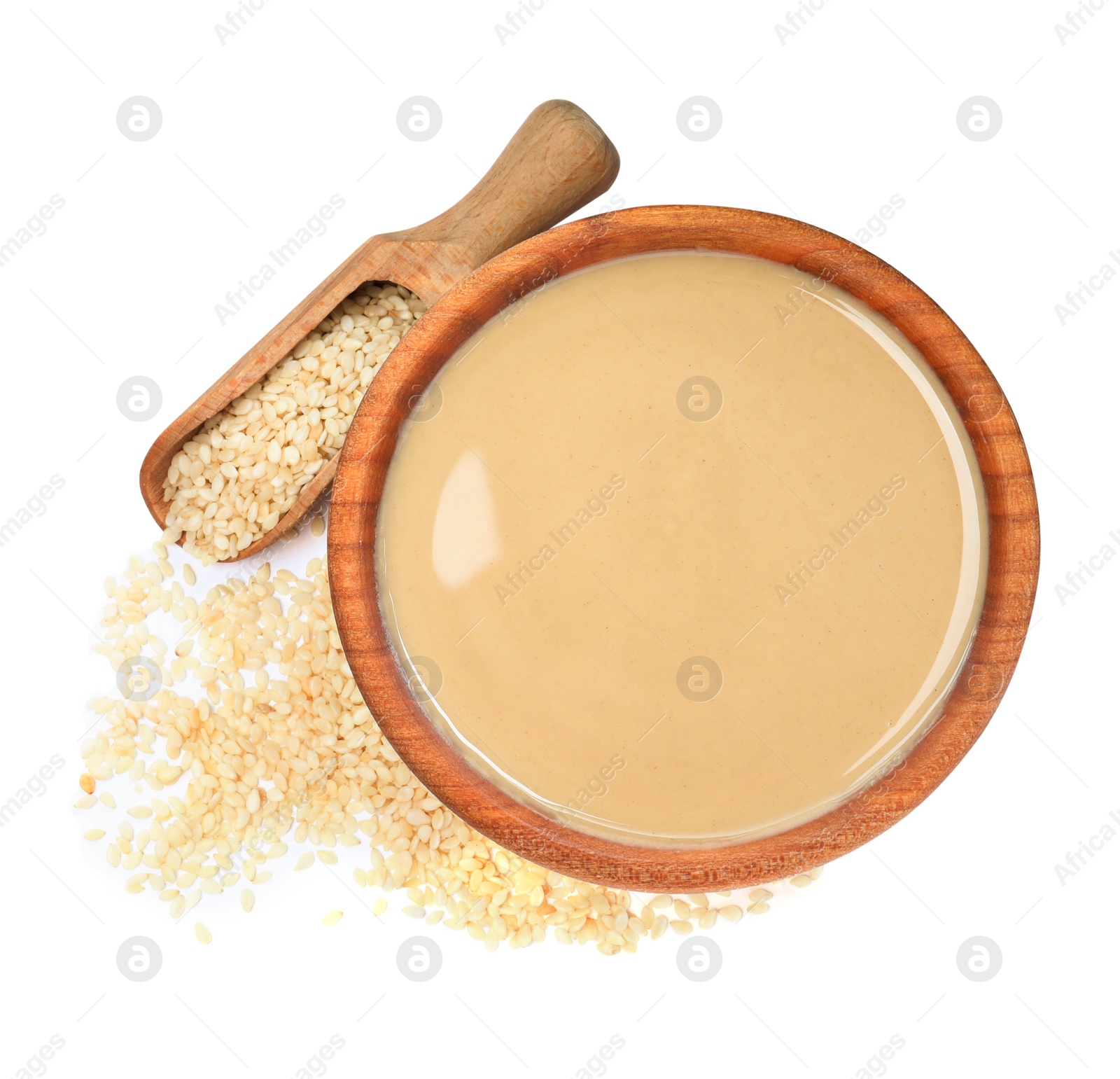 Photo of Tasty sesame paste in bowl, scoop and seeds on white background, top view