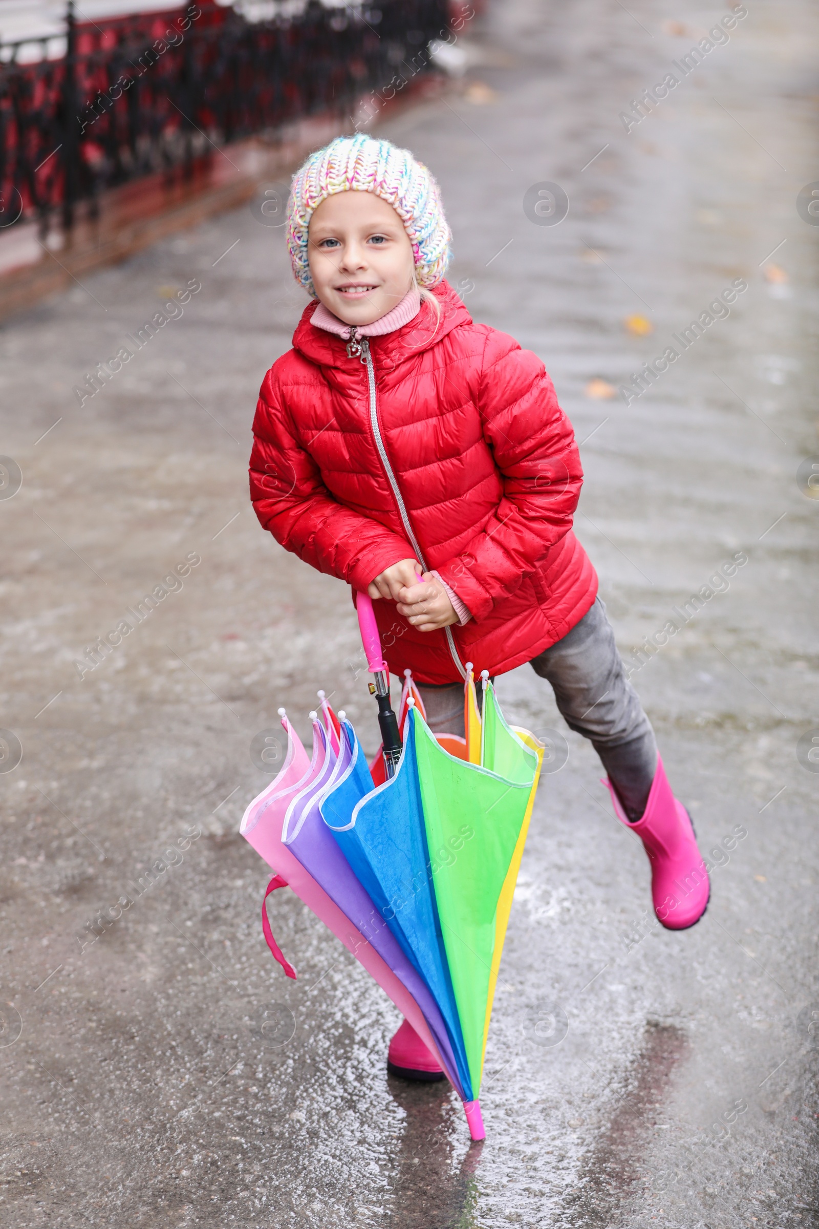 Photo of Little girl with umbrella in city on autumn rainy day