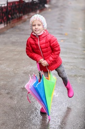 Little girl with umbrella in city on autumn rainy day