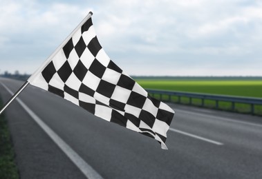 Image of Checkered racing finish flag and asphalt road outdoors