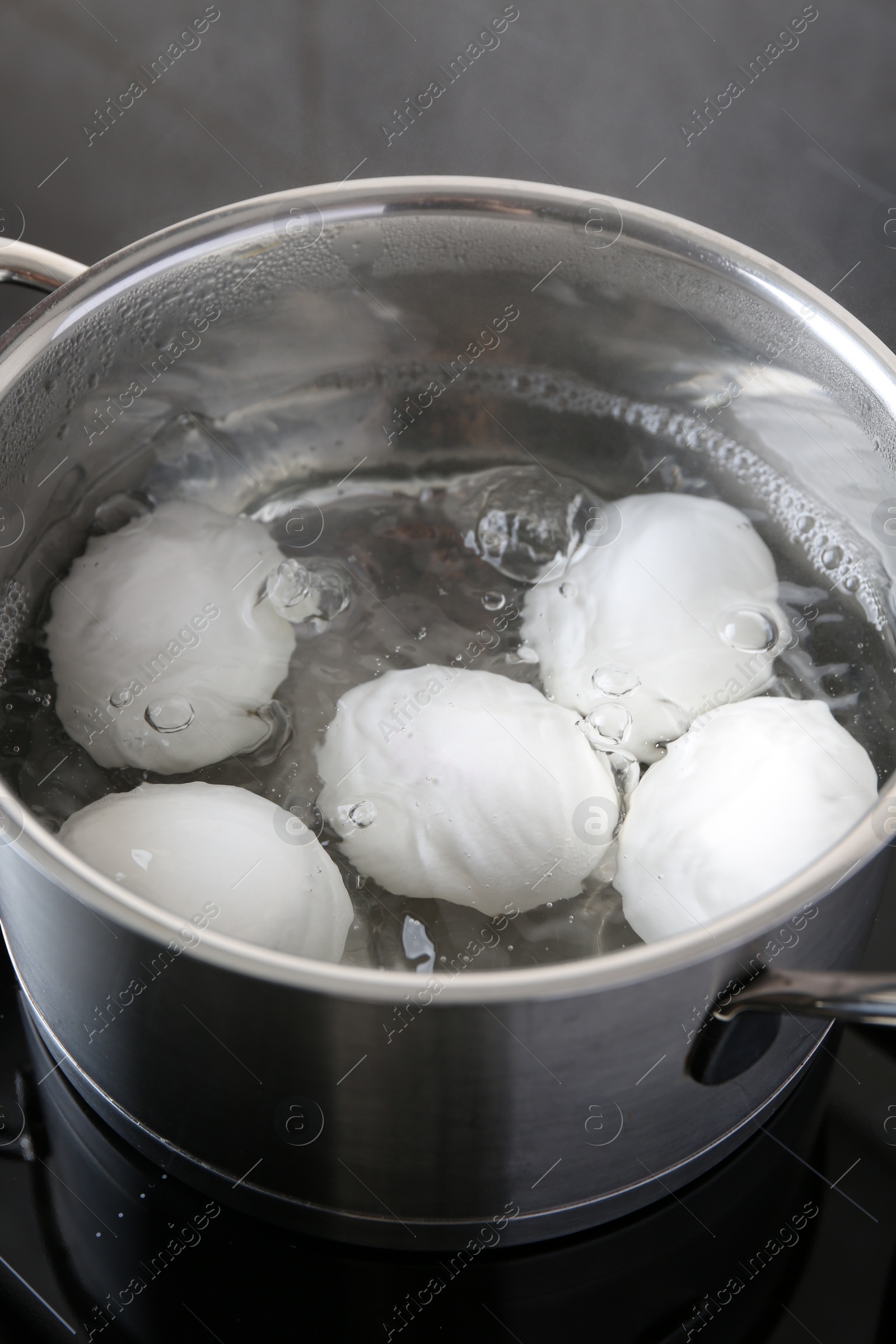 Photo of Chicken eggs boiling in pot on electric stove, closeup