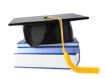 Photo of Graduation hat with gold tassel and stack of books isolated on white