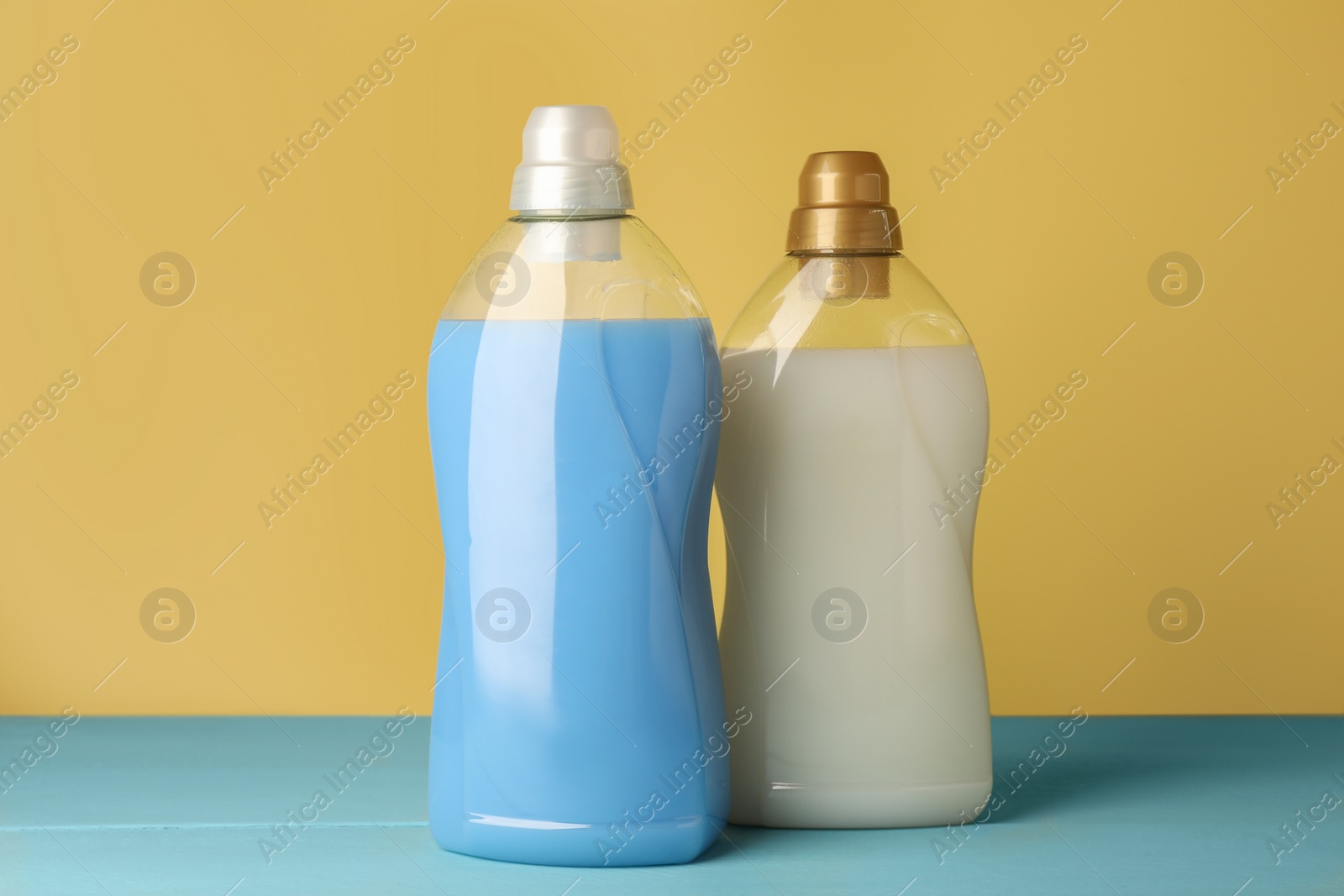 Photo of Bottles of fabric softener on light blue table