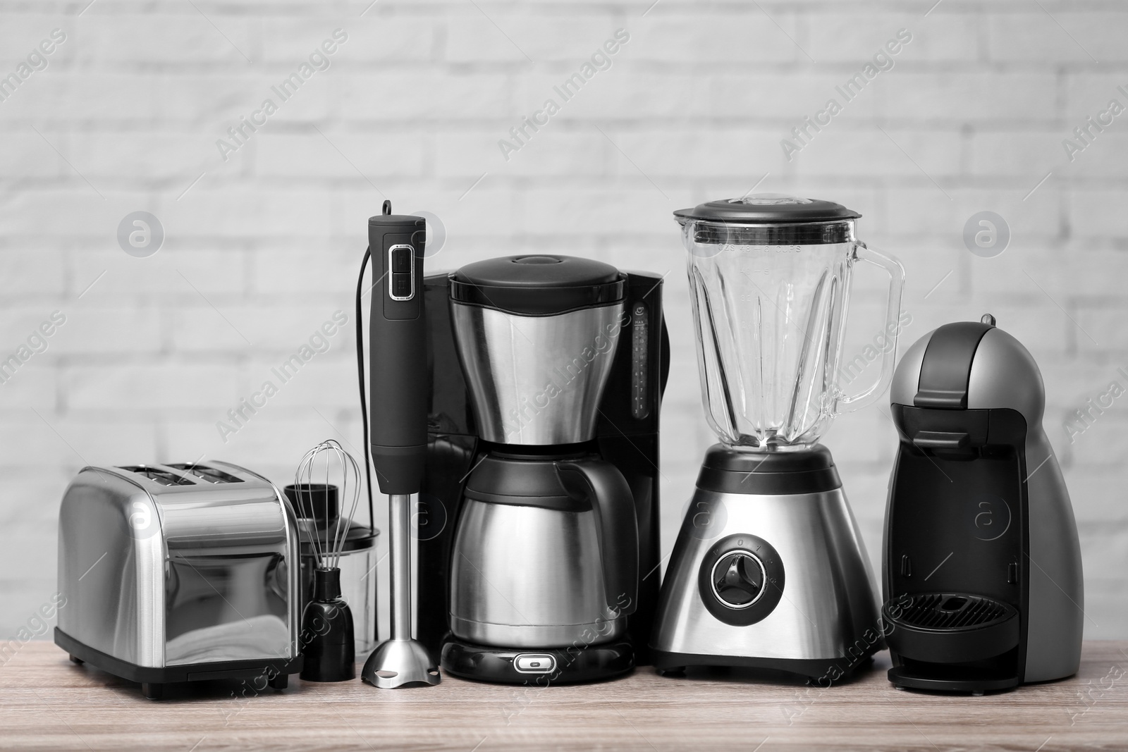 Photo of Kitchen appliances on table against brick wall background. Interior element