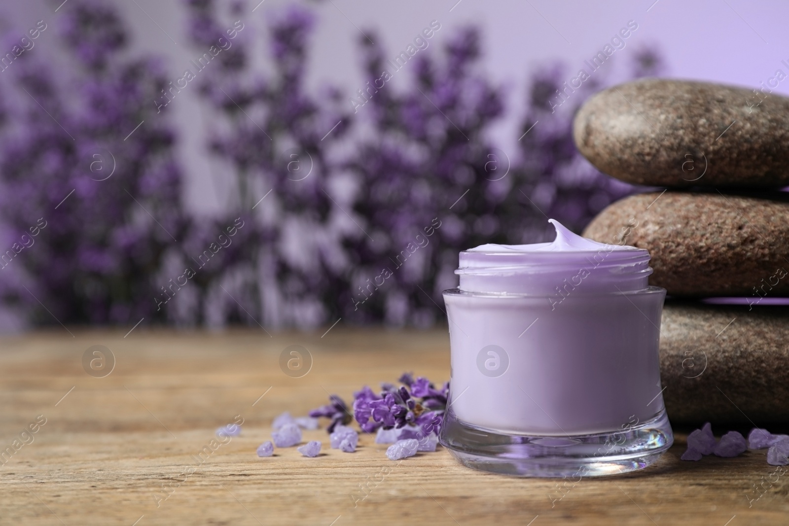 Photo of Stones, jar of cream and lavender flowers on wooden table. Space for text