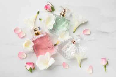 Luxury perfume and floral decor on white marble table, flat lay