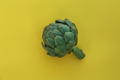 Photo of Whole fresh raw artichoke on yellow background, top view