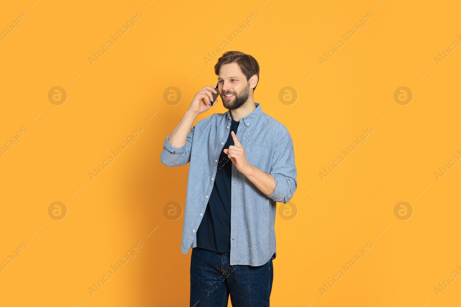 Photo of Man talking on smartphone against orange background