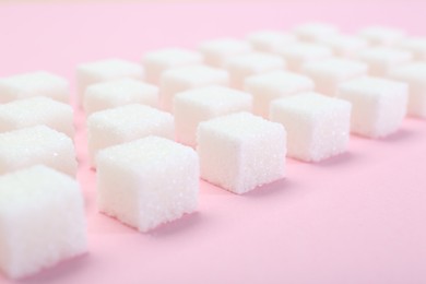 Photo of White sugar cubes on pink background, closeup