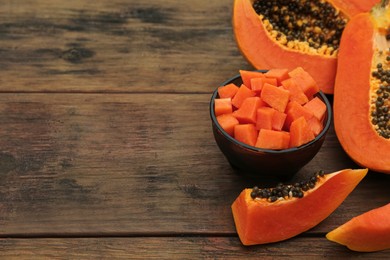 Photo of Tasty cut papaya fruits on wooden table. Space for text