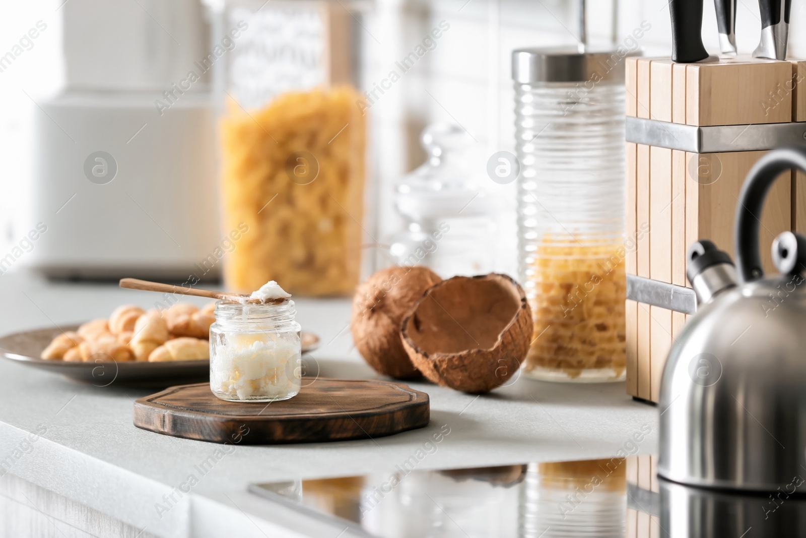 Photo of Jar with coconut oil on table in kitchen. Healthy cooking