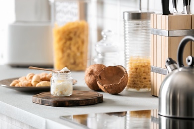 Jar with coconut oil on table in kitchen. Healthy cooking