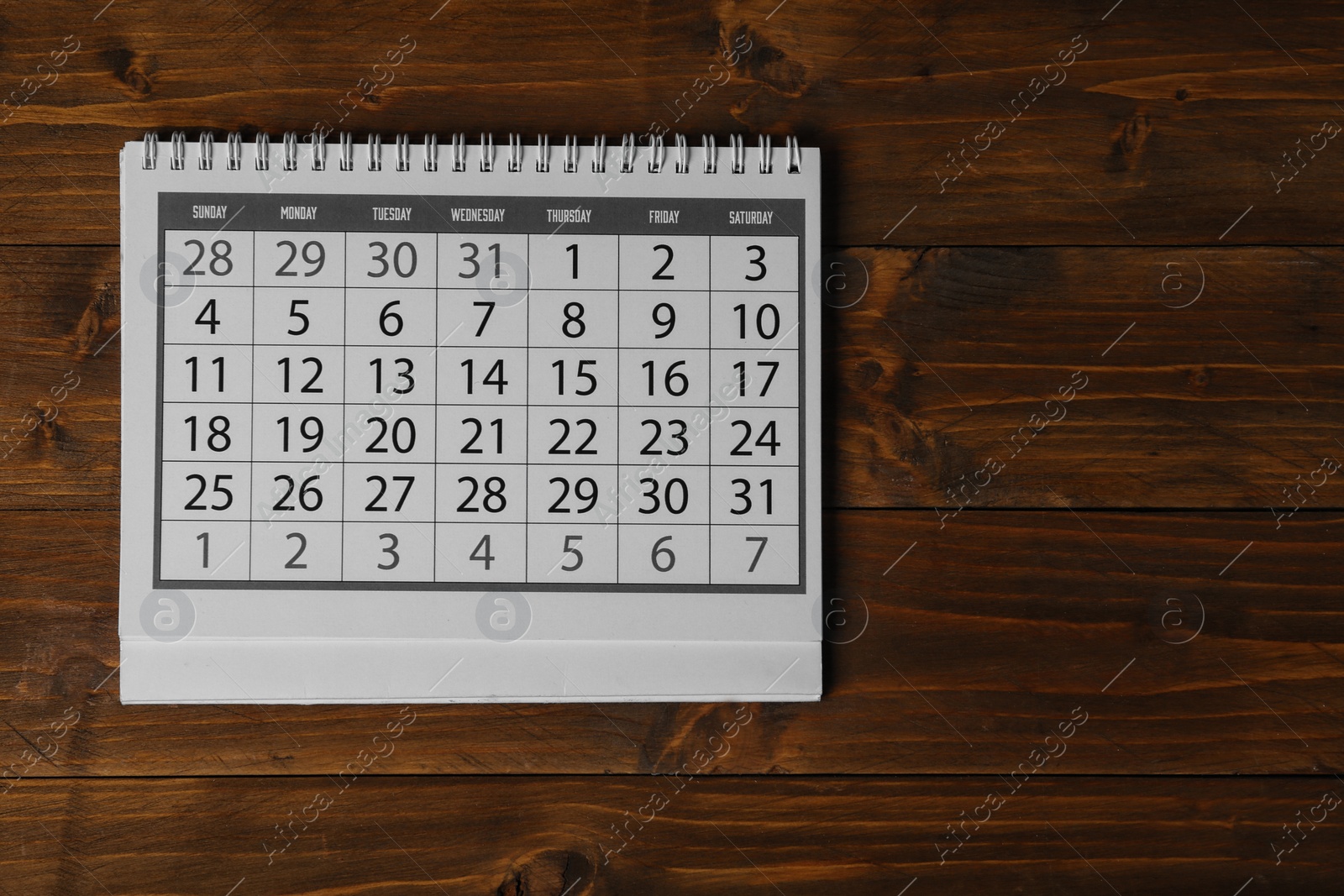 Photo of Paper calendar on wooden table, top view