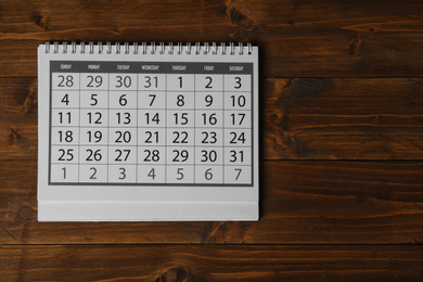 Paper calendar on wooden table, top view