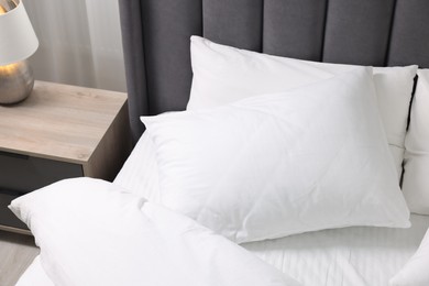 Photo of Soft white pillows and duvet on bed at home