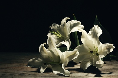 Photo of Beautiful lilies on dark background with space for text. Funeral flowers