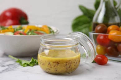 Tasty vinegar based sauce (Vinaigrette) in jar on white marble table, closeup