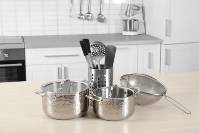 Set of clean cookware and utensils on table in kitchen