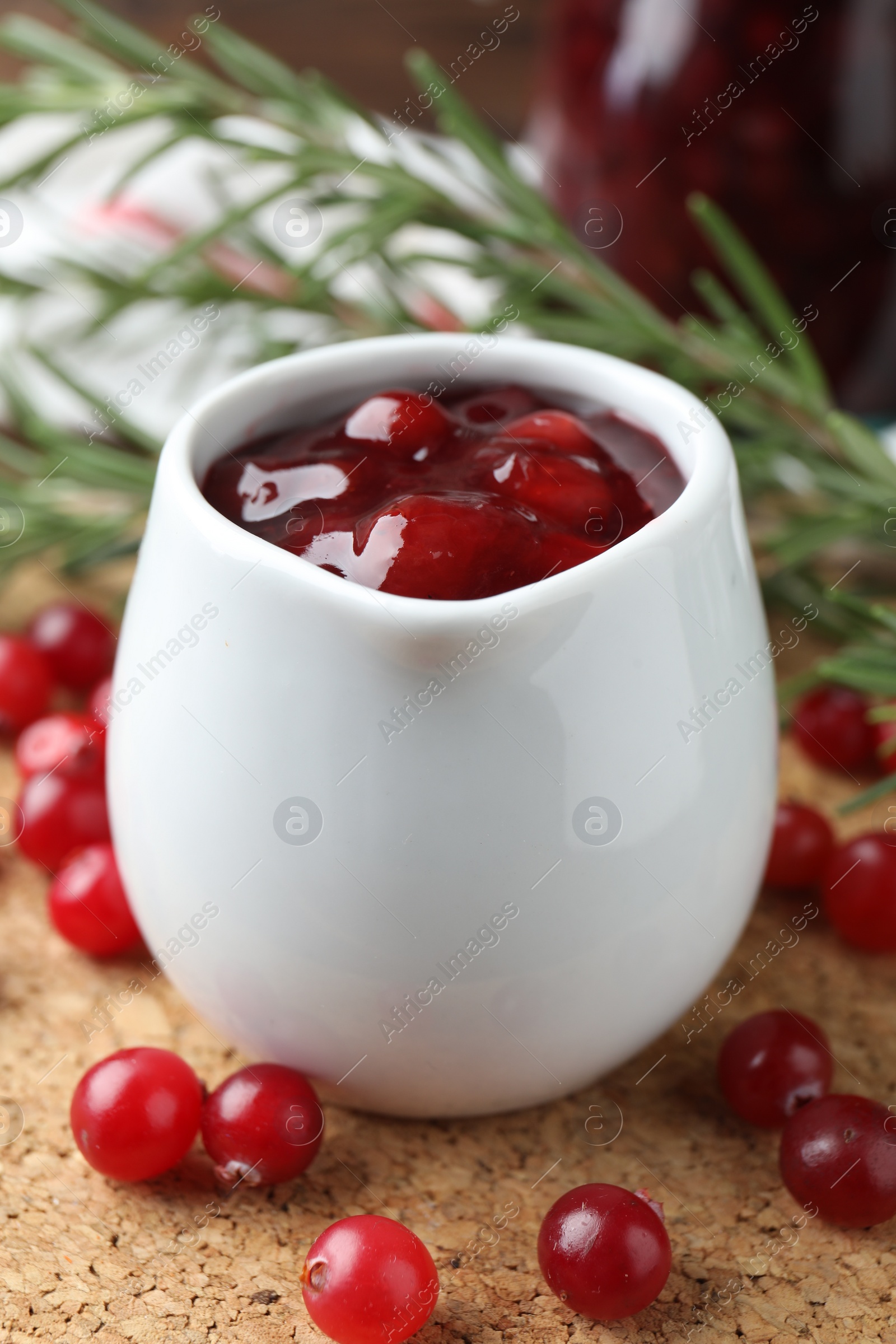 Photo of Cranberry sauce in pitcher and fresh berries on board, closeup