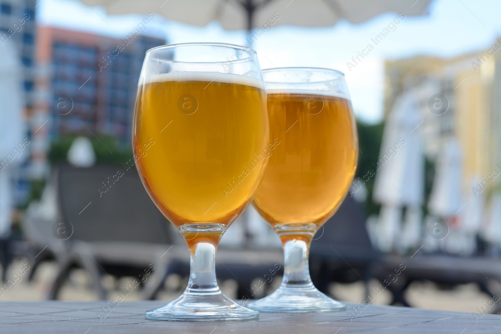 Photo of Cold beer in glass on beach, closeup