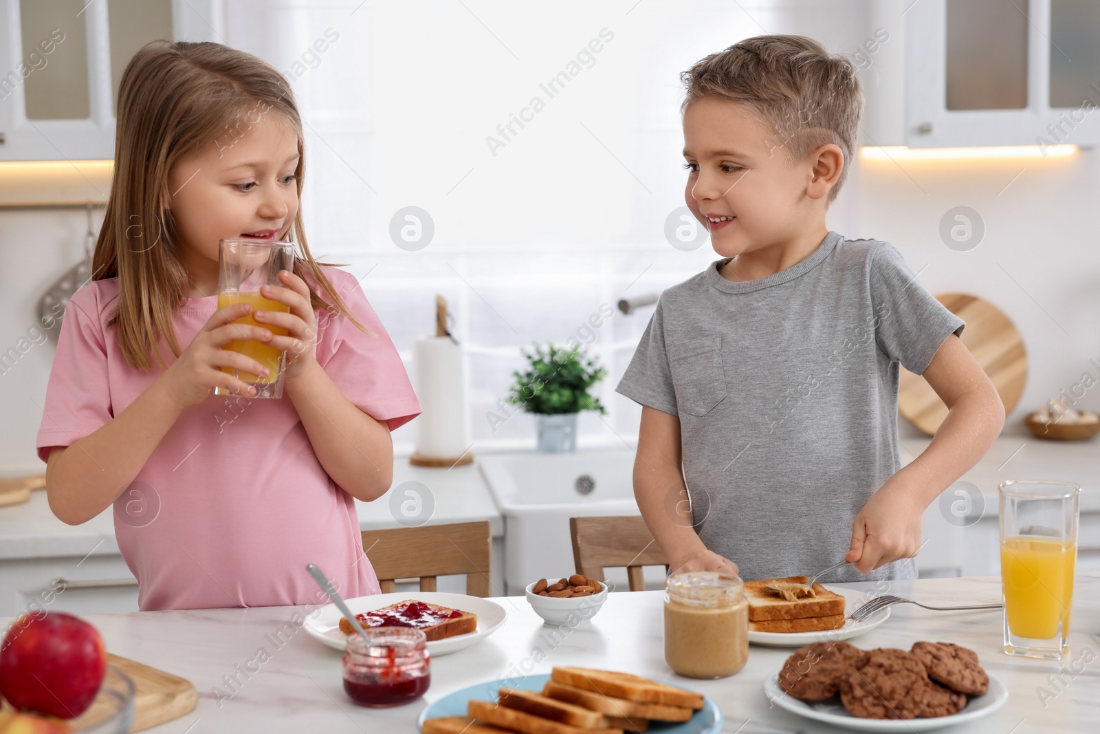 Photo of Little children having breakfast at table in kitchen