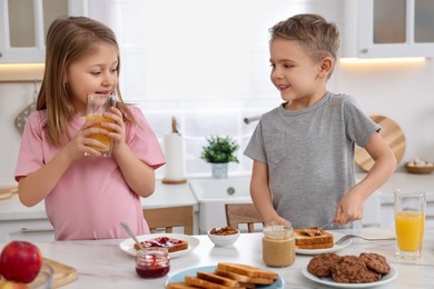 Photo of Little children having breakfast at table in kitchen