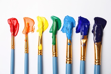 Set of brushes with different paints on white background, flat lay. Rainbow colors