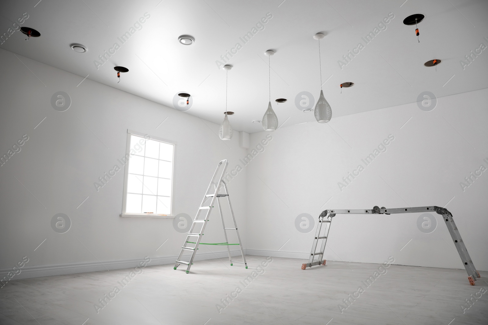 Photo of Empty room with stretch ceiling and ladders