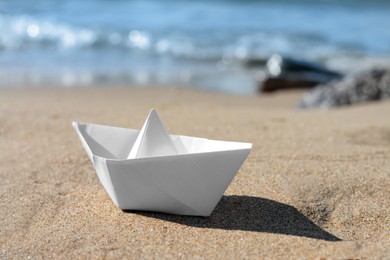 Photo of White paper boat near sea on sunny day, closeup