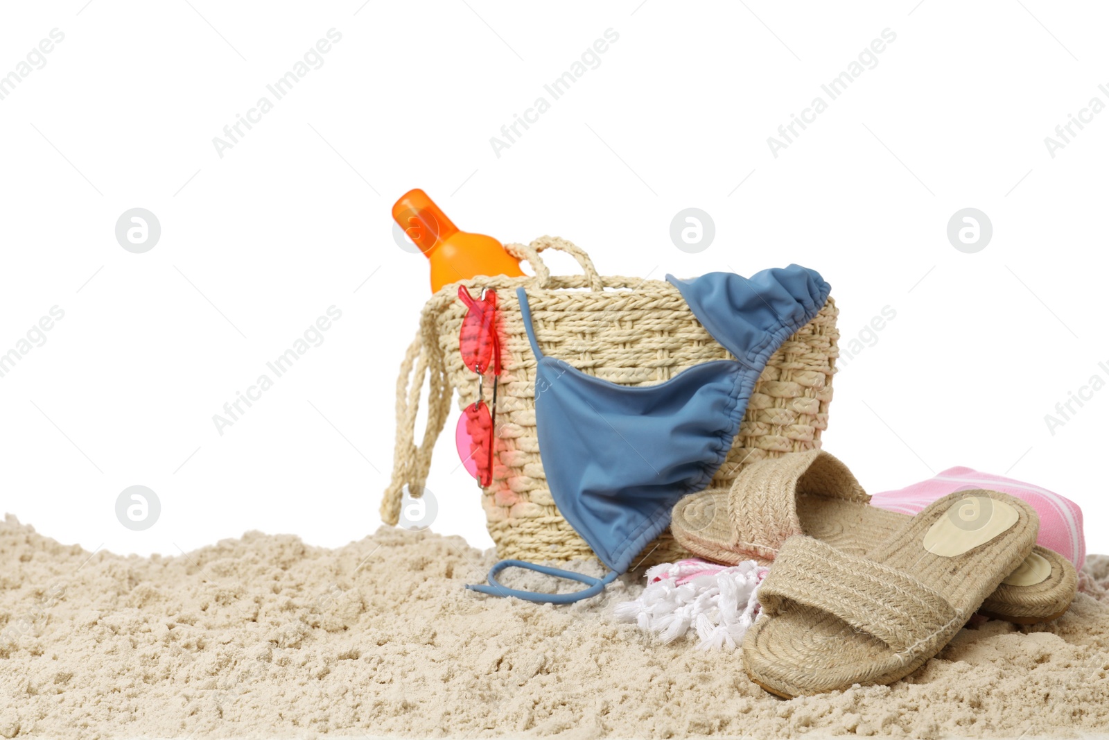 Photo of Stylish bag with beach accessories on sand against white background