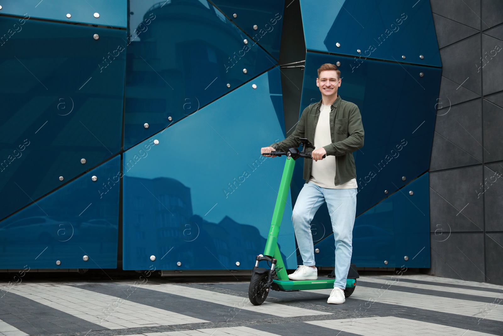 Photo of Happy man with modern electric kick scooter on city street, space for text