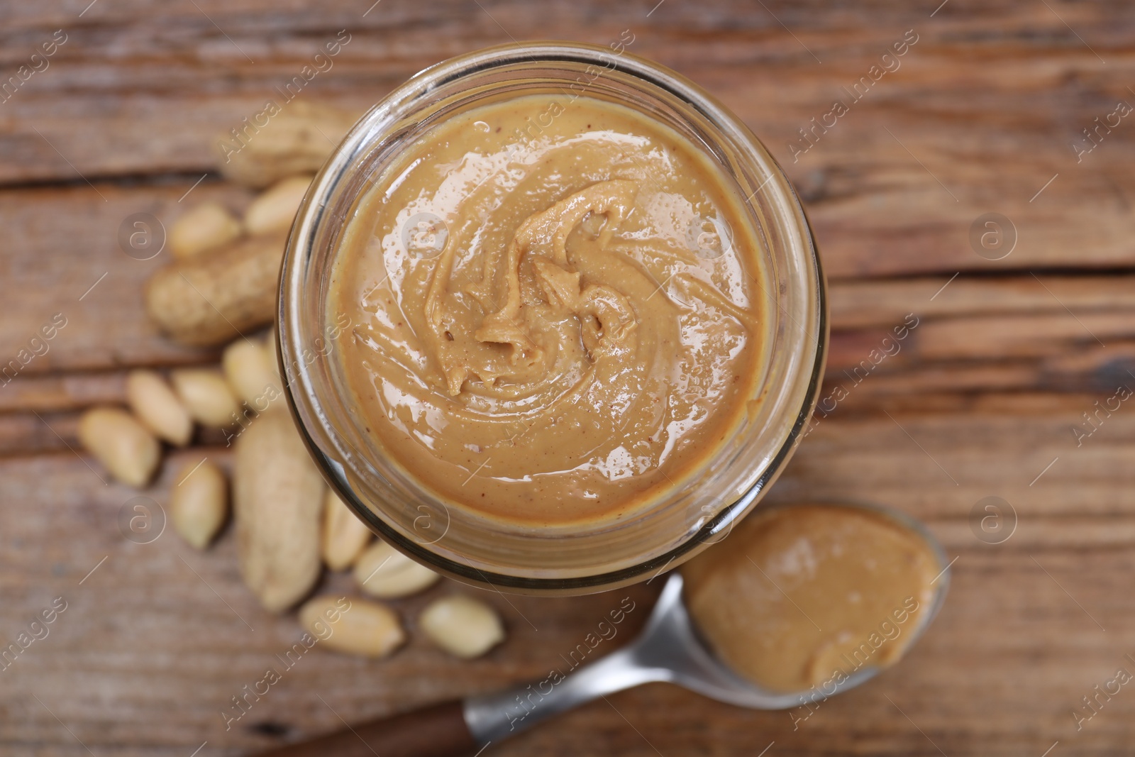 Photo of Tasty peanut nut paste in jar on table, top view