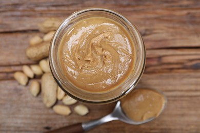 Photo of Tasty peanut nut paste in jar on table, top view