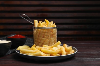 Tasty french fries and dip sauces on wooden table