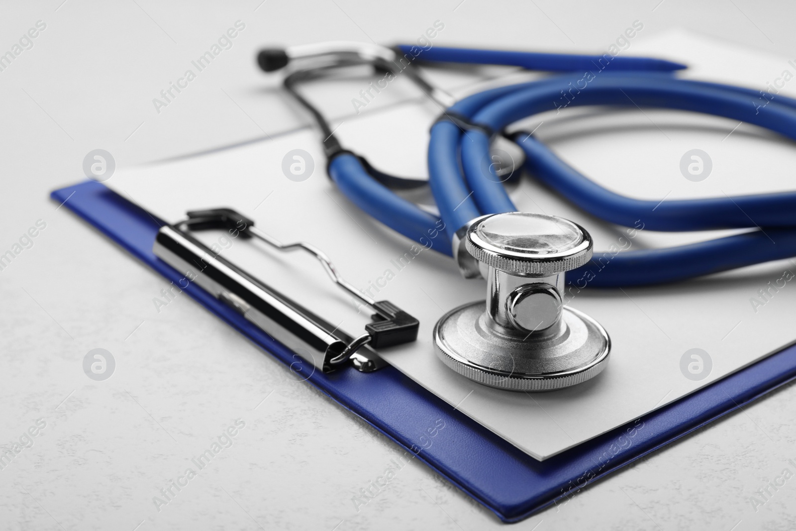 Photo of Clipboard with stethoscope on white background, closeup