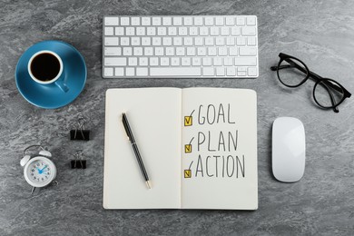 Photo of Flat lay composition of notebook with words Goal, Plan and Action on grey table