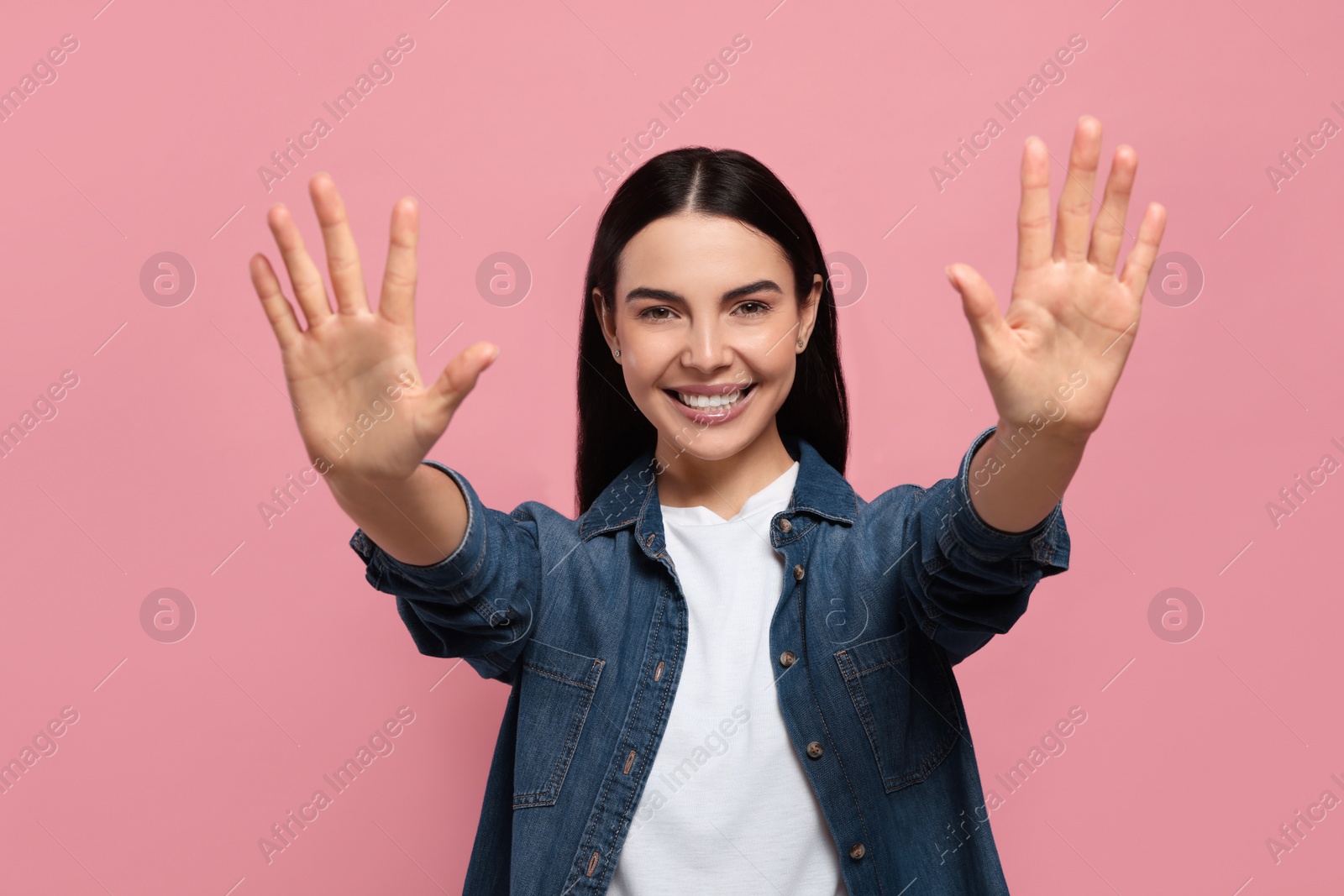 Photo of Happy woman giving high five with both hands on pink background