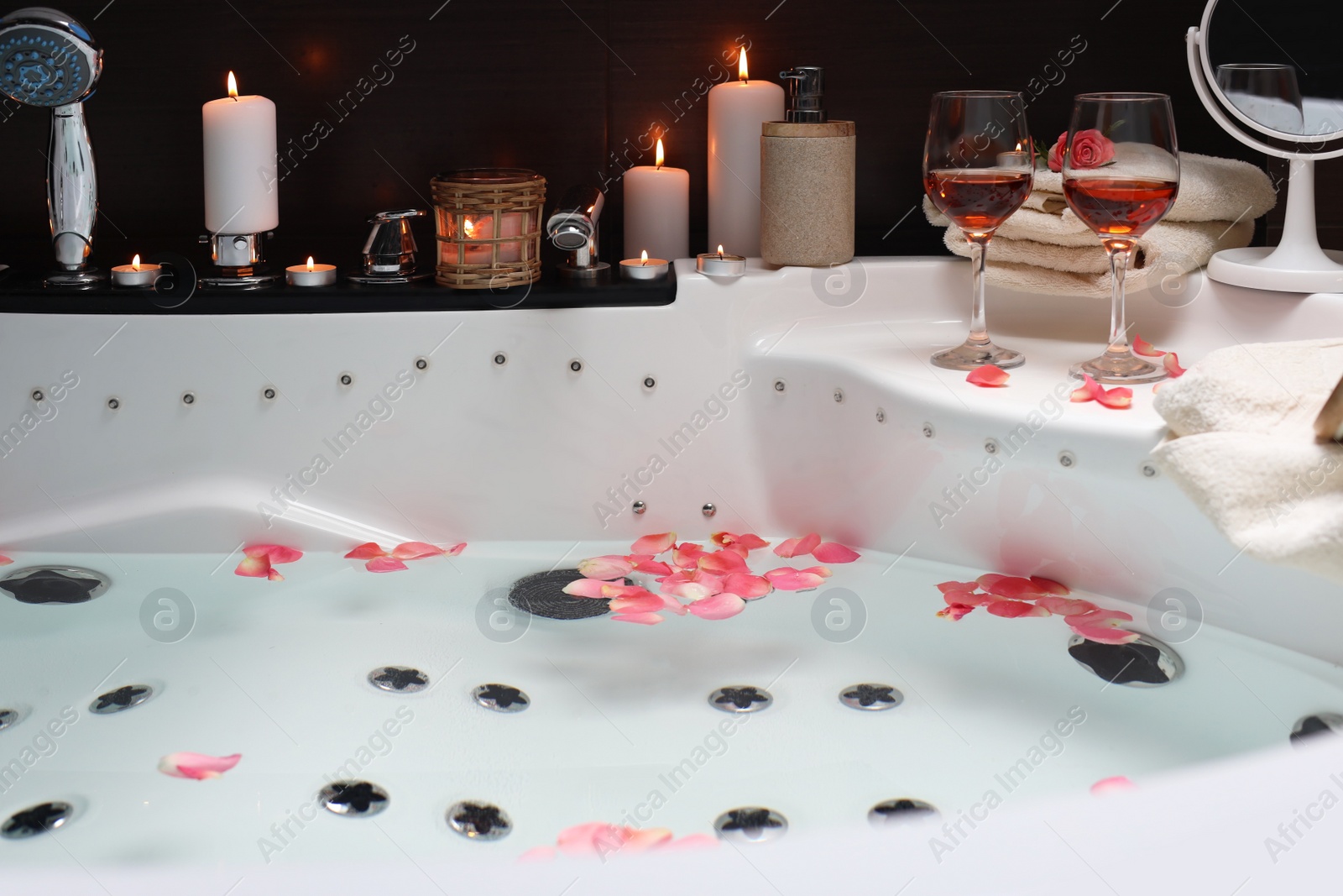 Photo of Bathtub with glasses of wine and candles indoors. Romantic atmosphere