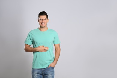 Photo of Happy healthy man touching his belly on light grey background, space for text