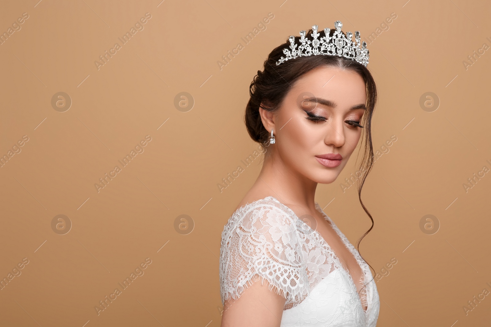 Photo of Beautiful young woman wearing luxurious tiara on beige background, space for text