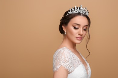 Photo of Beautiful young woman wearing luxurious tiara on beige background, space for text