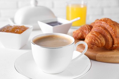 Photo of Fresh croissants, jams and coffee on white table, closeup. Tasty breakfast