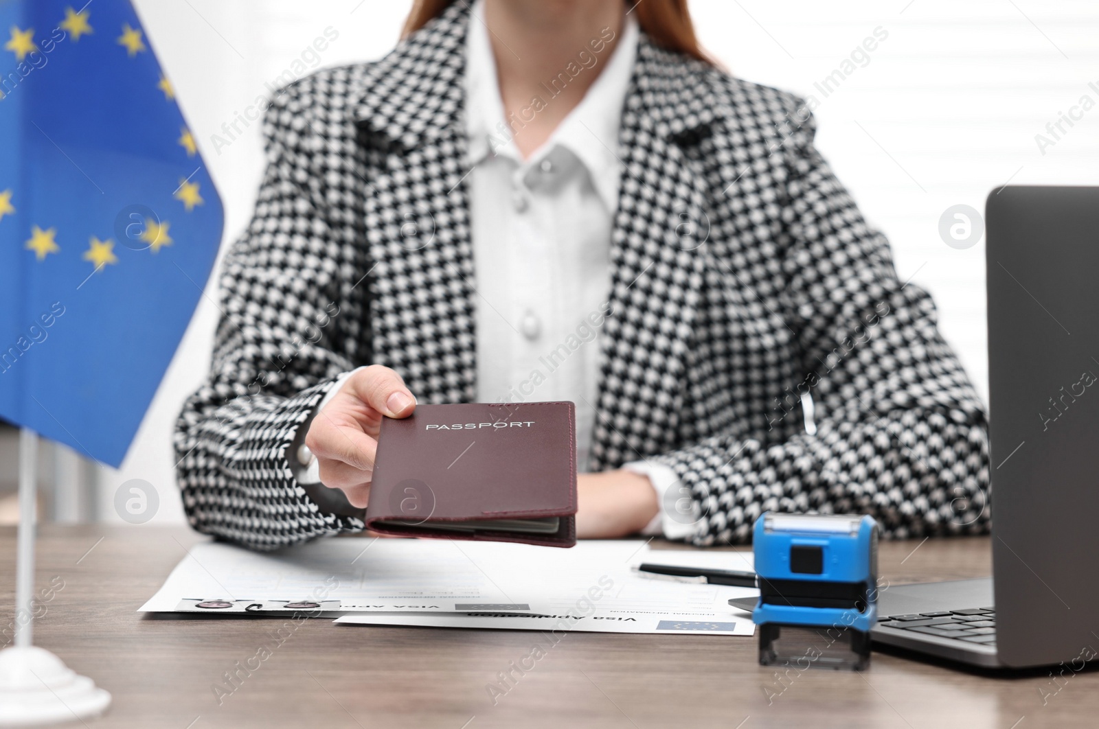 Photo of Immigration to European Union. Embassy worker with passport and documents at wooden table in office, closeup