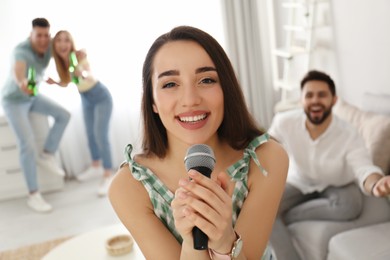 Photo of Young woman singing karaoke with friends at home