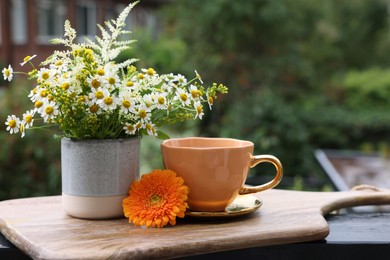 Cup of delicious chamomile tea and fresh flowers outdoors. Space for text