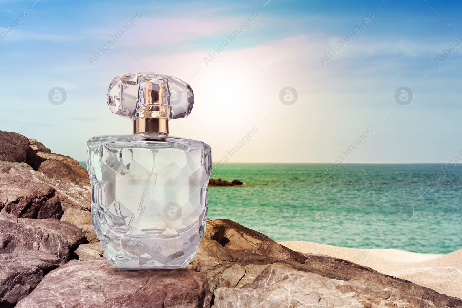 Image of Bottle of aquatic perfume on rock near ocean. Fresh sea breeze scent