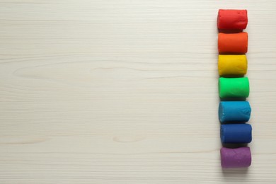 Photo of Different color play dough on wooden table, flat lay. Space for text