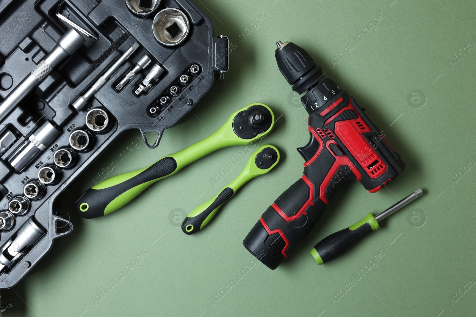 Photo of Electric screwdriver and accessories on pale green background, flat lay